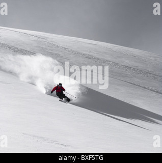 Un libero sciatore, sci verso la telecamera, facendo giri veloci sulla neve farinosa in La tomba, Francia Foto Stock
