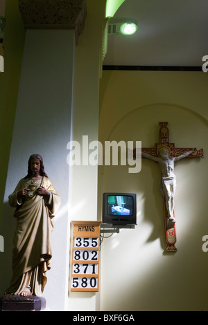 Gesù sulla croce con schermo TV all'interno presso San Lorenzo della chiesa cattolica a Feltham, Londra. Foto Stock