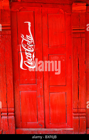 Nepal - Valle di Kathmandu - Bhaktapur - Coca Cola pubblicità dipinta su una porta Foto Stock