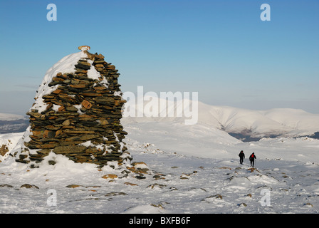 Alto vertice Spy cairn e walkers in inverno nel Lake District inglese. Skiddaw in background Foto Stock