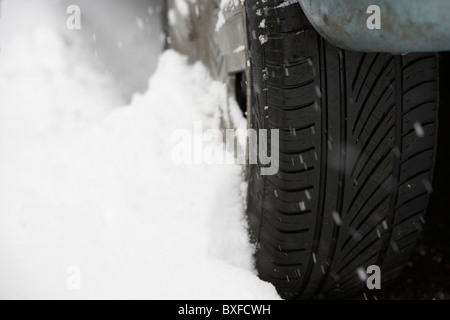 Snow drifting fino contro un pneumatico autovettura in un freddo inverni nevosi giorno Foto Stock