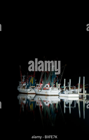 Gamberi commerciale barche ormeggiate in porto con luce riflettendo in acqua calma . Swansboro, North Carolina, STATI UNITI D'AMERICA Foto Stock