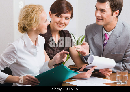 Un gruppo di tre giovani uomini di affari che discutiamo di un nuovo piano di lavoro in ufficio Foto Stock