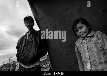 Un spostato l'uomo con sua figlia sta in piedi di fronte alla sua casa nella baraccopoli di Ciudad Bolívar, Bogotà, Colombia. Foto Stock