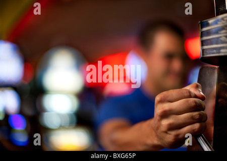 Native American uomo tirando la leva della slot machine di Casino Foto Stock