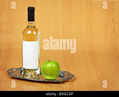 Still-life - una bottiglia di vino bianco e una mela verde su un vassoio Foto Stock