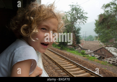 Bimba bionda guardando fuori della finestra su un treno passeggeri in viaggio da Pechino a Datong, Cina. Foto Stock