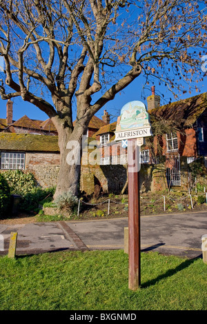 Segno del villaggio e le case del villaggio verde a Alfriston sulla South Downs East Sussex England con un blu cielo invernale Foto Stock