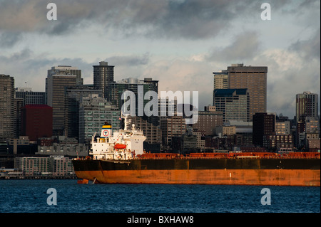 Una nave portacontainer linee fino ai contenitori di carico nel porto di Seattle il terminale lungo il fiume Duamish con la skyline di Seattle. Foto Stock