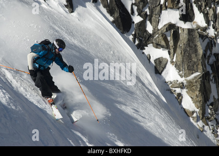Un libero sciatore sciare giù un couloir in La tomba, Francia. Gli sciatori mano è in un calco in gesso. Foto Stock