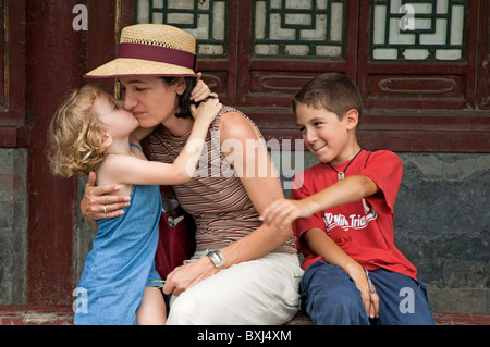 Madre condivide un momento di gara con i suoi due bambini mentre prendendo una pausa nel Parco Behai, Pechino, Cina. Foto Stock