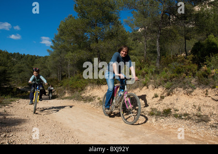 Padre e figlio avente fun cavalcare le loro mountain bike insieme su una strada sterrata, Vitrolles, Provenza, Francia. Foto Stock