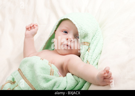 Dieci settimane vecchio incantevole piccola bambina bimbo avvolto in asciugamano stretching le braccia Foto Stock