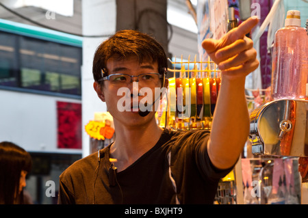 Venditore di pubblicità dei suoi prodotti presso il Ladies Market, Mong Kok, Kowloon, Hong Kong, Cina Foto Stock