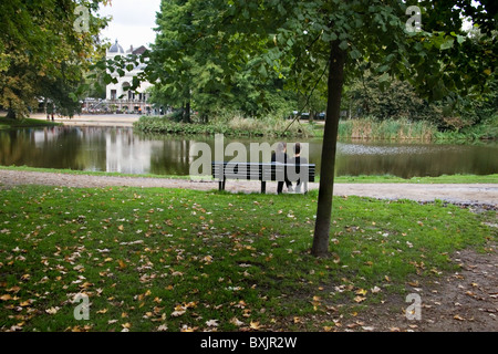 Due persone a sedersi su una panchina presso lo stagno del Parco di Vondel Amsterdam Foto Stock