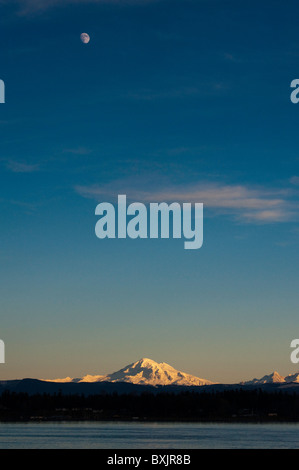 La luce del tramonto tocca Mt. Baker, Washington appena dopo la luna sorge sopra il vulcano in un bel cielo azzurro. Foto Stock