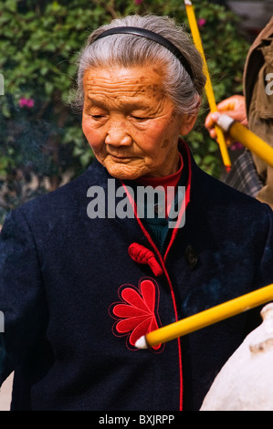 Vecchi espressiva donna asiatica lighting incenso presso il tempio buddista di Hong Kong Cina Foto Stock