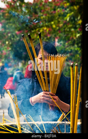 Espressivo giovane donna asiatica ad offrire incenso al tempio buddista di Hong Kong Cina Foto Stock