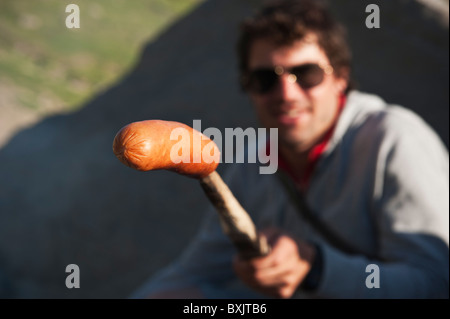 L uomo può contenere fino insaccato su stick cotti sul fuoco all'aperto Foto Stock