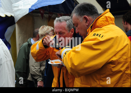 Due uomini dal RNLI godere un po' di zuppa di pesce durante il festival del pesce in aberaeron Foto Stock