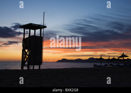 Red Sky all'alba su Santa Margalida beach, Can Picafort, Maiorca (Mallorca), Spagna, con bagnino lookout post in silhouette Foto Stock