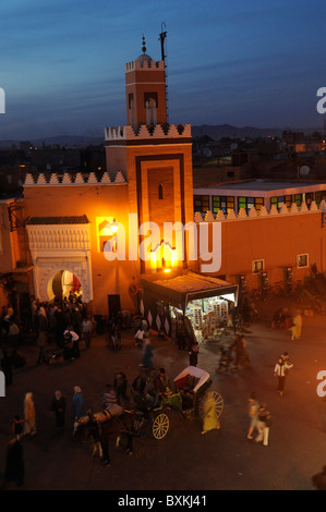 Moschea e occupato Djemaa el Fna luogo di incontro di notte a Marrakech Foto Stock