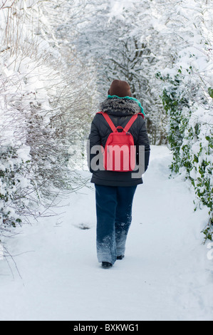 Donna che cammina lungo una coperta di neve il percorso a Redditch, Worcestershire. Foto Stock