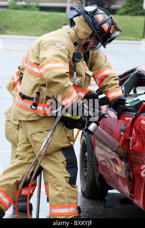 Due vigili del fuoco utilizzando le ganasce della vita per entrare in una vettura dopo un incidente Foto Stock