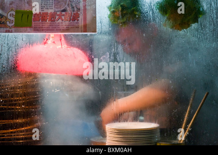 Uomo asiatico prepara il cibo in stallo all'aperto sulla strada di città nel centro di Hong Kong Cina Foto Stock