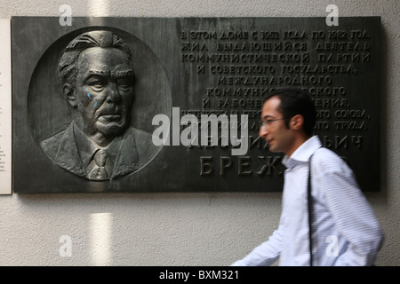 L'uomo passando una lapide commemorativa dalla casa di Leonid Brezhnev a Mosca nel Museo del Muro di Berlino in Germania. Foto Stock