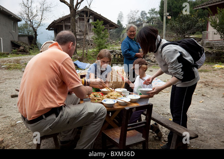 Un gruppo di escursionisti avente il pranzo preparato in un piccolo villaggio isolato a ovest della Cina. Foto Stock