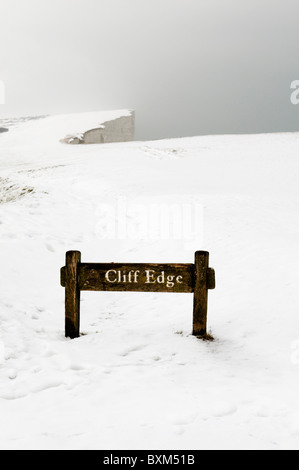 Cliff Edge segno a Beachy Head, East Sussex, Regno Unito nella neve con scarsa visibilità Foto Stock