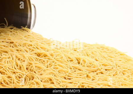 Una grande pentola di spaghetti noodles plain versato su sfondo bianco. Foto Stock