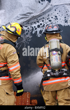 Vigili del fuoco estinguere un incendio con fusione della plastica in una stanza Foto Stock