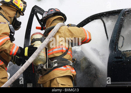 I vigili del fuoco su un hoseline scontri a fuoco auto Foto Stock