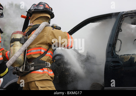 I vigili del fuoco su un hoseline scontri a fuoco auto Foto Stock