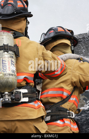 I vigili del fuoco su un hoseline scontri a fuoco auto Foto Stock