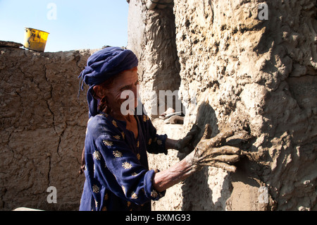 Kheshgi camp per i rifugiati afghani. Dopo il diluvio. 76 anni Khalthoum Safk cerotti la sua casa ricostruita con fango. Foto Stock