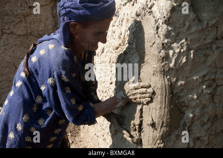 Kheshgi camp per i rifugiati afghani. Dopo il diluvio. 76 anni Khalthoum Safk cerotti la sua casa ricostruita con fango. Foto Stock