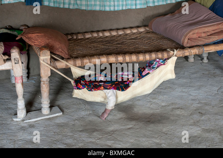 Il Pakistan dopo il diluvio.Kheshgi camp per i rifugiati afghani. Il bambino dorme in un amaca infilate sotto un letto di corda. Foto Stock