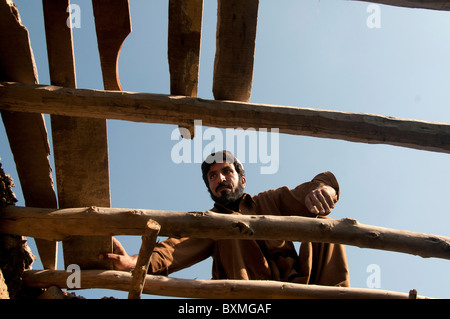 Il Pakistan dopo il diluvio..Kheshgi camp per i rifugiati afghani. Uomo che fa un tetto per la sua casa da vecchi listoni. Foto Stock