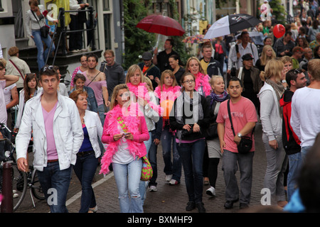 Persone che camminano giù Prinsengracht durante il Gay Pride, molti vestiti di rosa e con il rosa boas Foto Stock