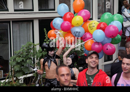 Persone che camminano lungo Prinsengracht durante il Gay Pride Amsterdam, un uomo e una donna che portano palloncini Foto Stock