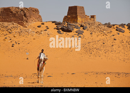 Ragazzo a dorso di cammello vicino a piramidi a Nubian faraoni e Re necropoli di Meroe ,Nubia, Sudan Foto Stock