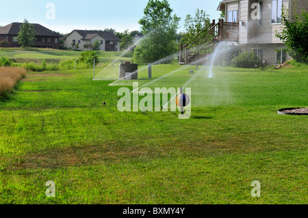 In terra-acqua degli sprinkler un prato in una suddivisione di Wichita, Kansas, Stati Uniti d'America. Foto Stock