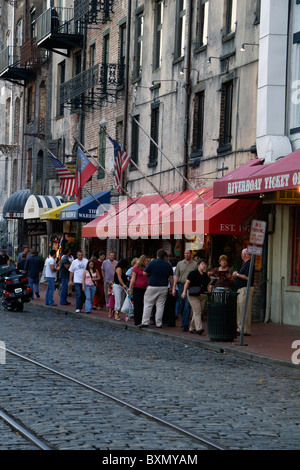 Gruppi di persone si affollano il marciapiede lungo la via fluviale di Savannah, GA, Stati Uniti d'America. Foto Stock