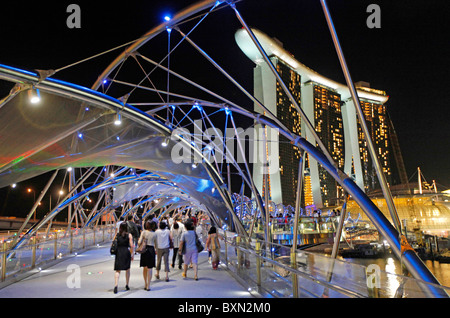 Singapore: Helix Bridge di notte con il Marina Bay Sands Resort Hotel e Centro Commerciale per lo Shopping nel backgrounnd Foto Stock