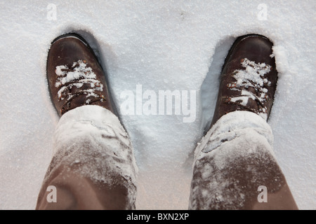 Guardando verso il basso a snowy stivali in pelle e pantaloni in un campo di un'escursione sulle colline di Quantock in Somesret Foto Stock