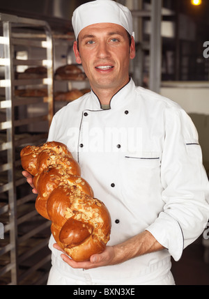 Sorridente Baker una focaccia appena cotta di pane dolce challah nelle sue mani Foto Stock