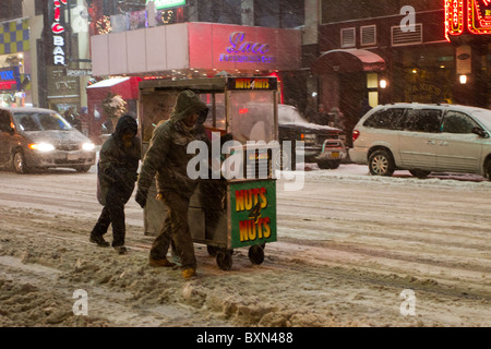 I fornitori di prodotti alimentari spingere i loro carrello giù Broadway durante una bufera di neve che ha coperto la città di New York in più di due metri di neve. Foto Stock